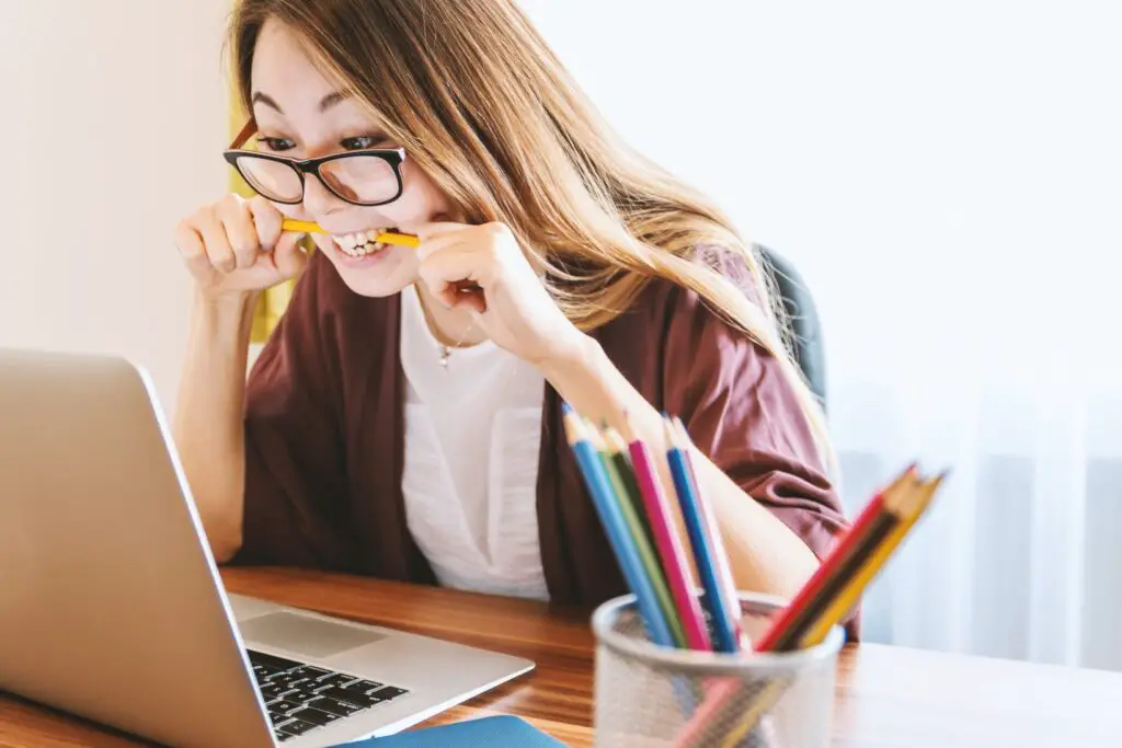 girl at computer biting on pencil