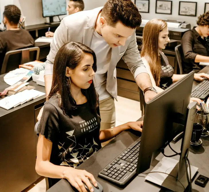 man looking over the shoulder of a student at a computer