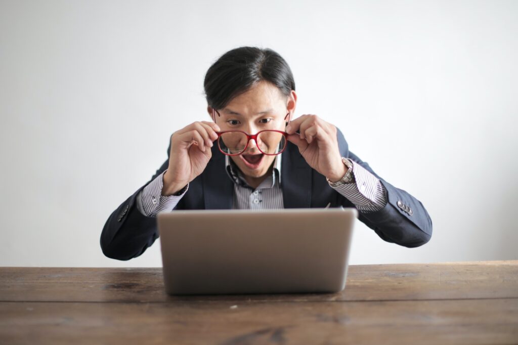 man showing a lot of emotion in front of a laptop computer