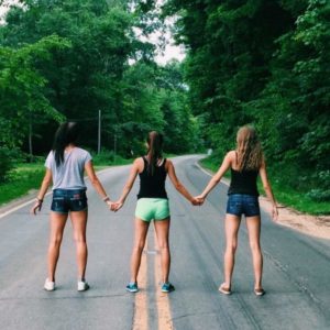 3 girls standing in the middle of the road holding hands