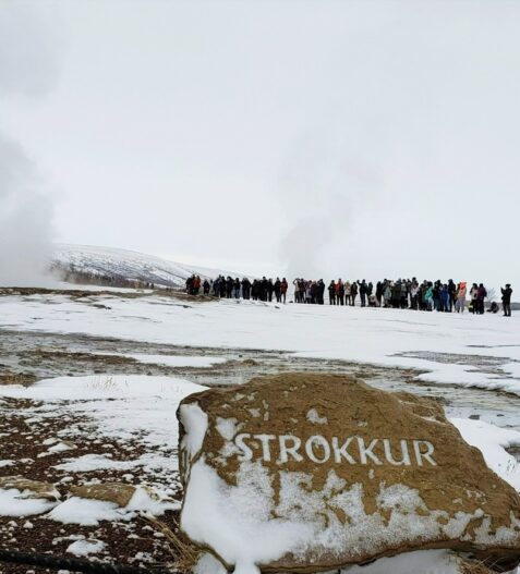 crowd of people around steaming Strokkur geysir in Iceland along Golden Cirlce driving route