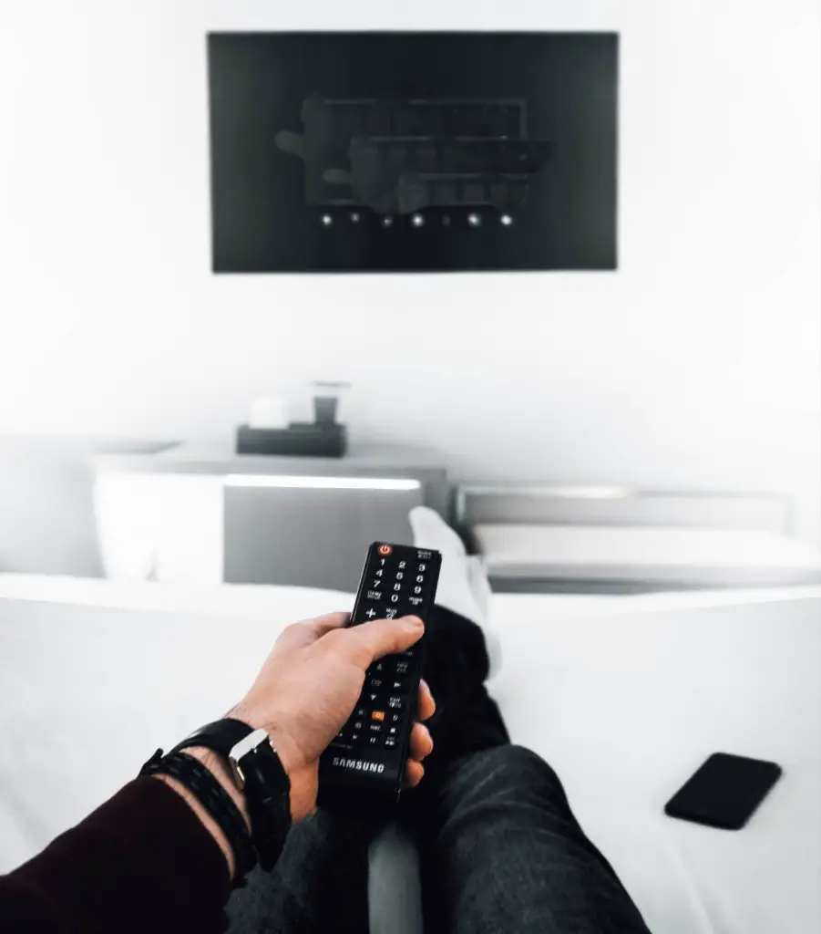 man holding remote in front of a tv