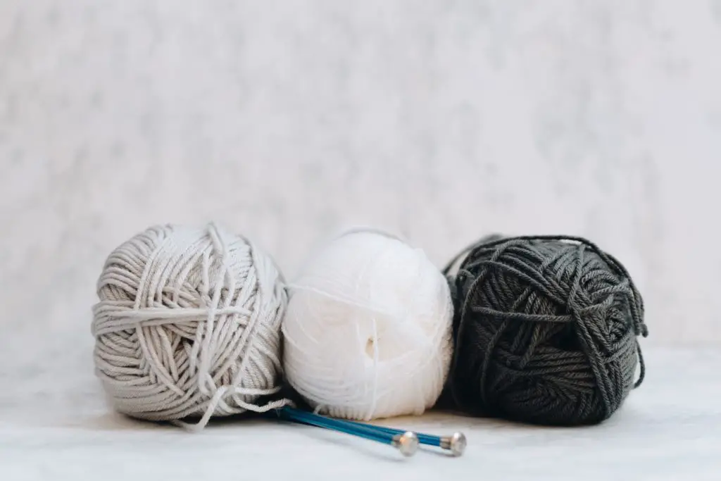 3 balls of yarn and knitting needles