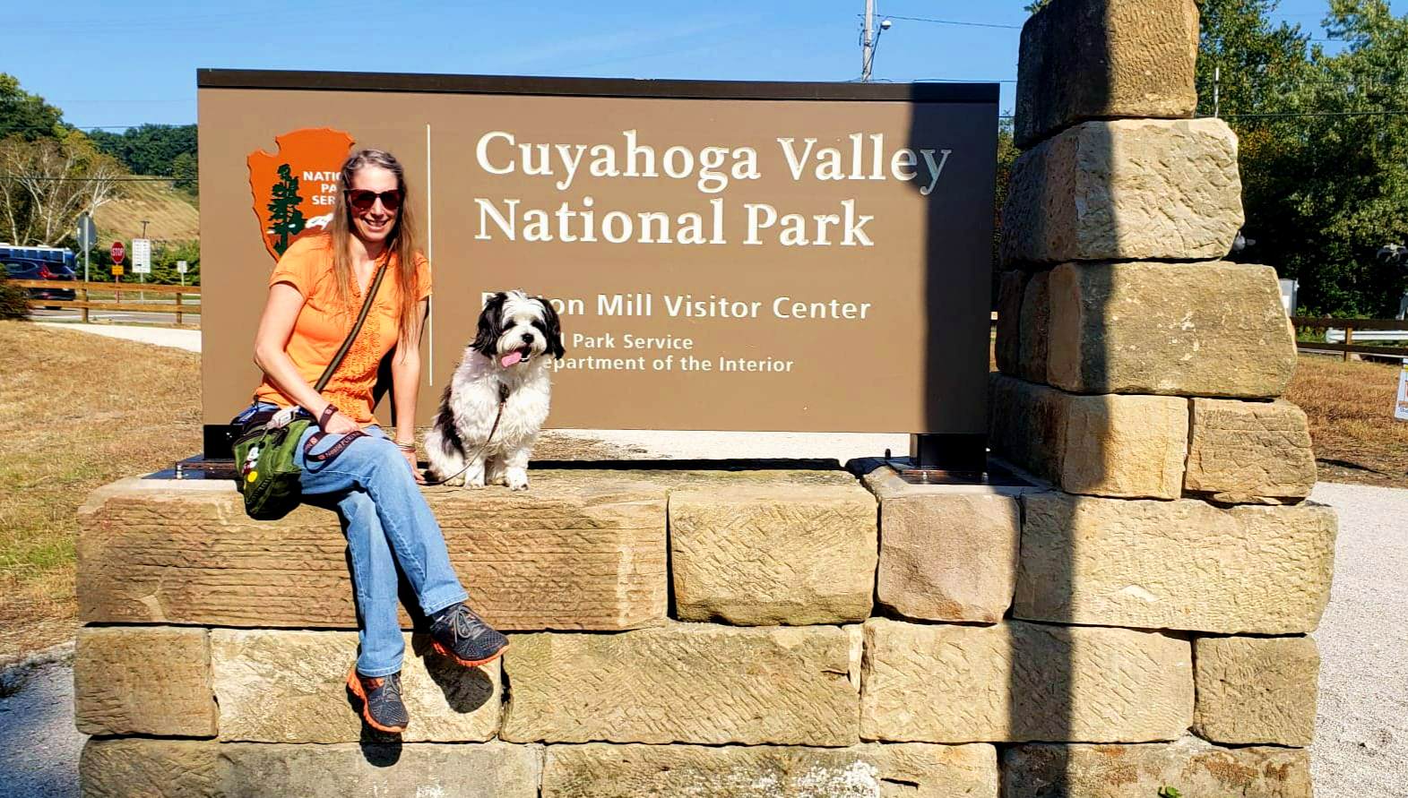lady and dog sit at the Cuyahoga Valley National Park sign