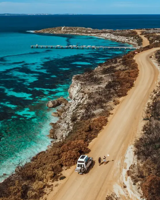 car and people walking on a dirt road next to Vivonne Bay