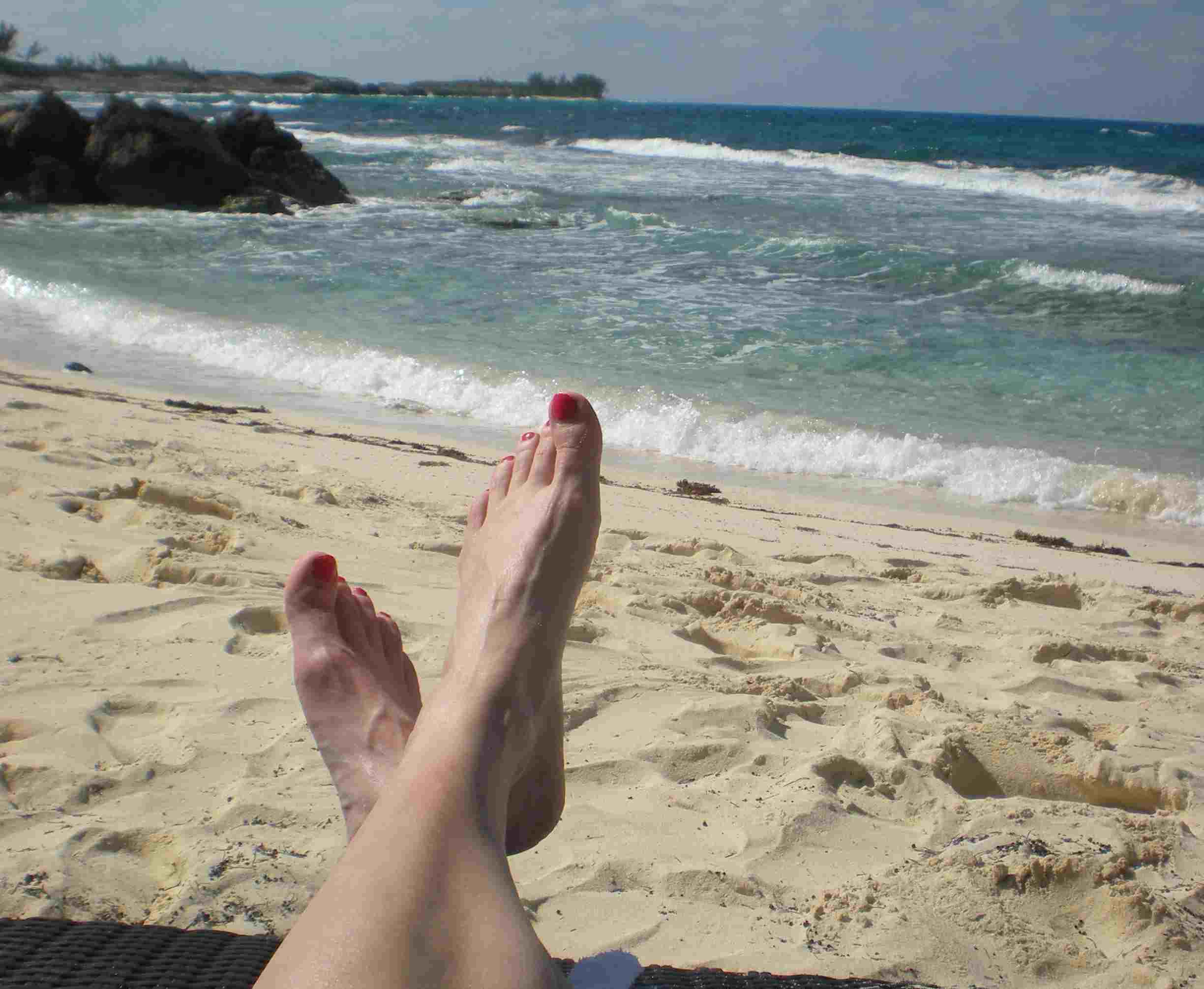 feet propped up on a beach during a stress-free vacation