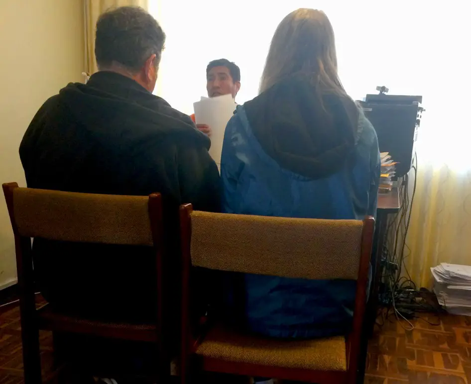 2 people sitting in front of a desk waiting for their visa to be approved at the embassy