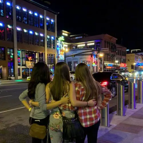 three girls standing and admiring the lights on broadway on a Nashville weekend trip