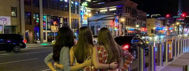 three girls standing and admiring the lights on broadway on a Nashville weekend trip