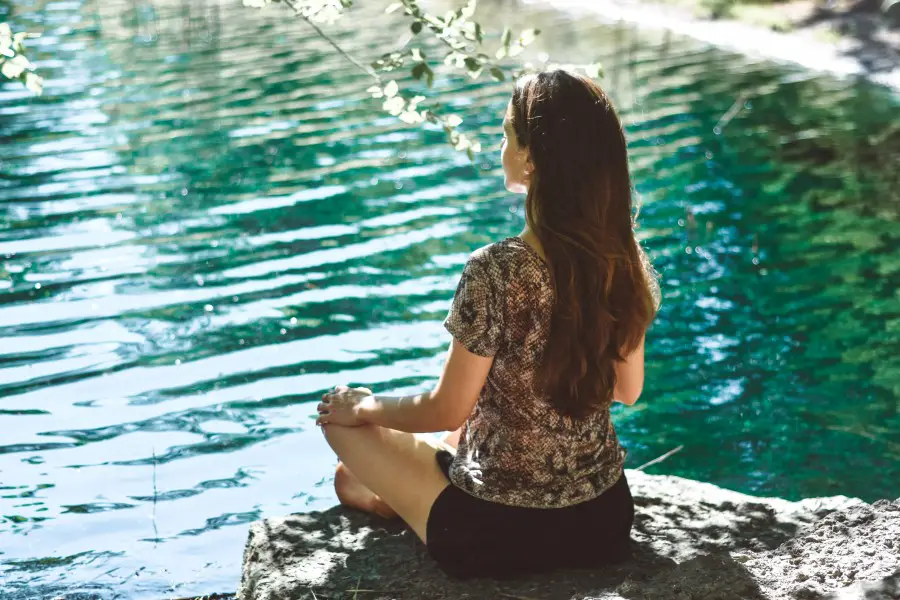 woman practicing yoga outdoors in front of a lake