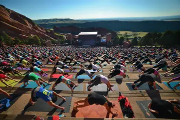 lots of people doing yoga at red rocks in a yoga pose on the bleachers