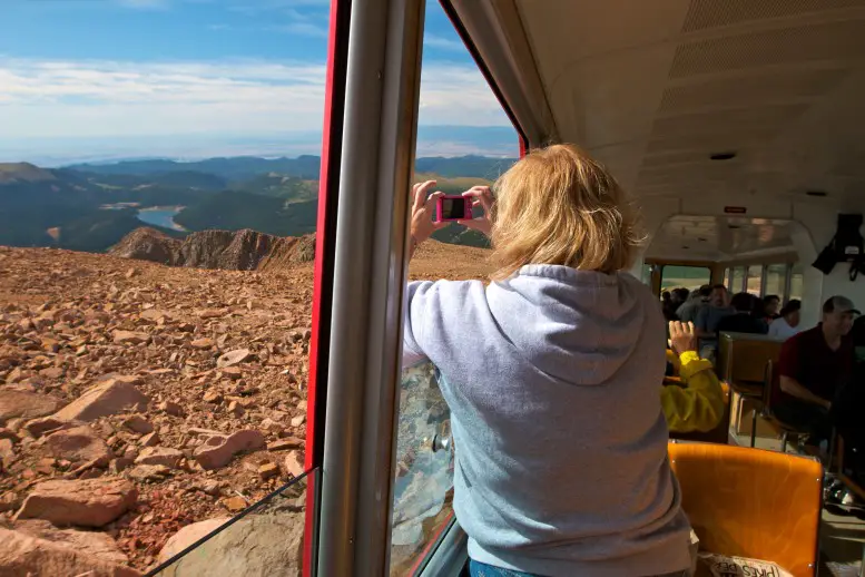 woman looking out a train car at mountain scenery from the Pikes Peak Cog Railway