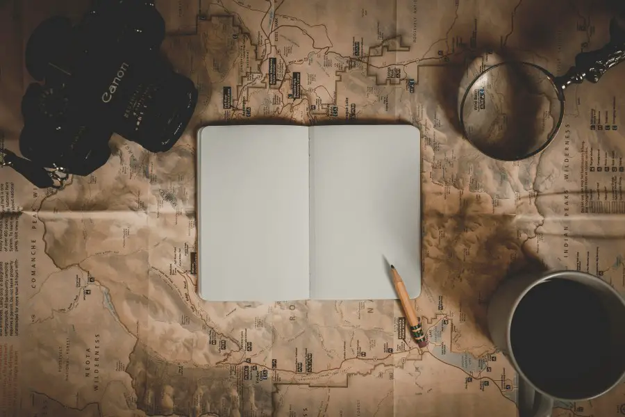 magnifying glass and notebook on a map