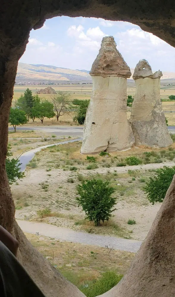 looking through a cave window in Monks Valley at a fairy chimney on a 2 day itinerary in Cappadocia
