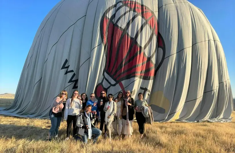 tour group posing in front of hot air balloon on the ground in cappadocia turkey