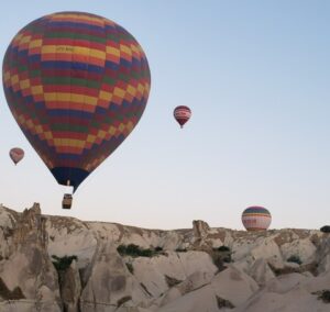 several hot air balloons floating over the Cappadocia landcape during hot air balloon rides in Turkey
