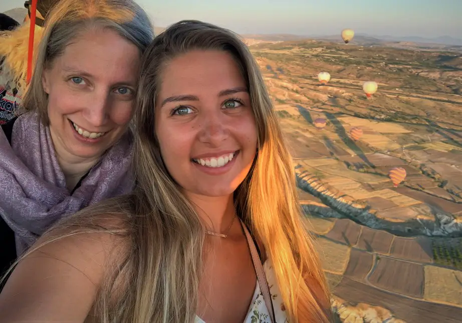 mother daughter pose in hot air balloon basket with balloon in the background in cappadocia turkey