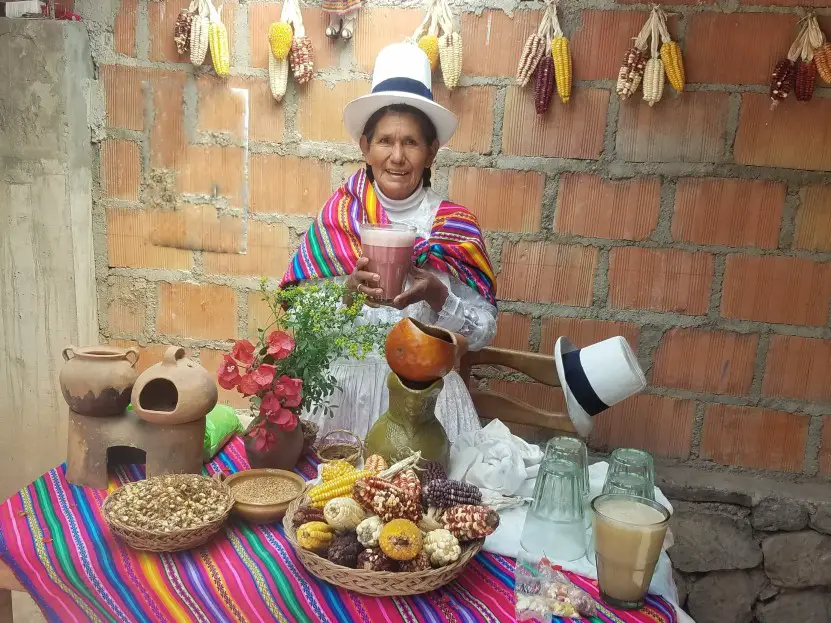 lady holding a glass of purple chicha at a Chicheria in Peru in Media Luna