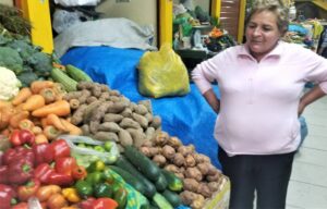 Lady standing with all the potatos and typical food of Peru