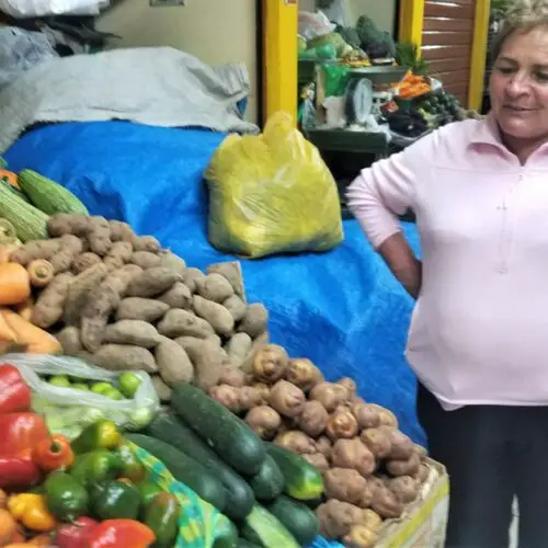 Lady standing with all the potatos and typical food of Peru