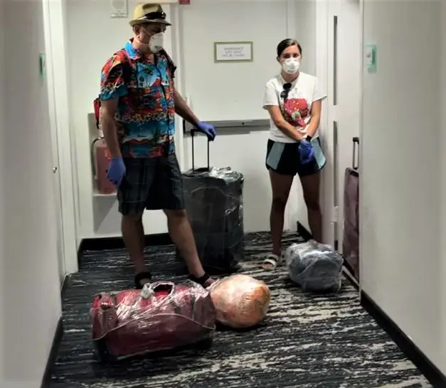 2 people standing in the hallway with saran wrapped luggage
