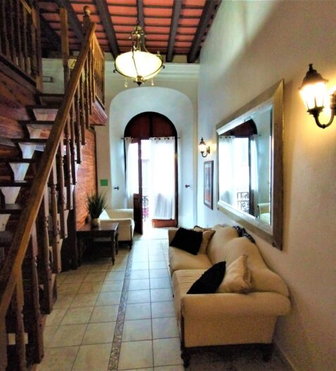 couches and stairway in a living room with an open door to a balcony in a suite hotel in old san juan puerto rico