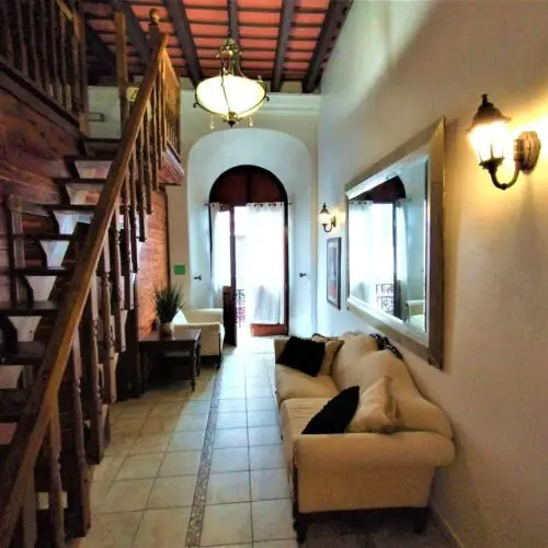 couches and stairway in a living room with an open door to a balcony in a suite hotel in old san juan puerto rico