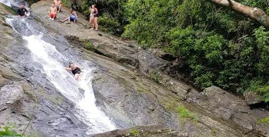 people in a natural water slide waterfall in Puerto Rico