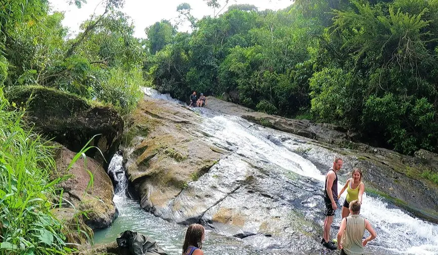 people gathered around a small waterfall going down a natural slide rock in Puerto Rico