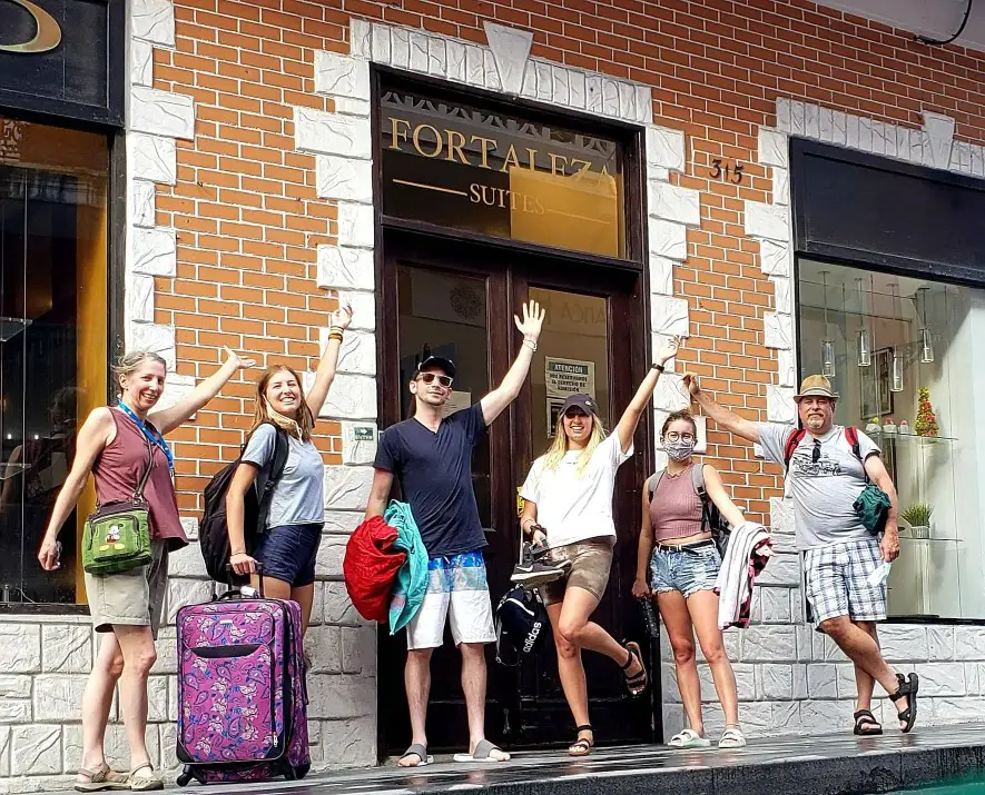 family of six stands outside the on the street in front of the lobby of a hotel in Puerto Rico before cruise