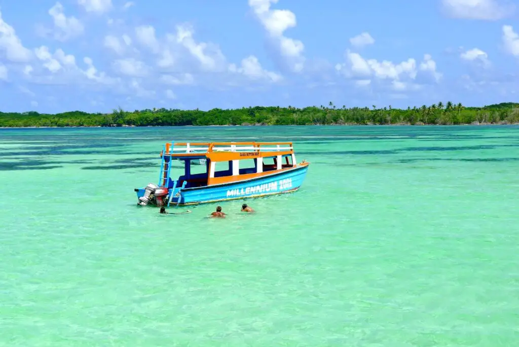 boat in the aqua caribbean water with trees in the background in Tobago