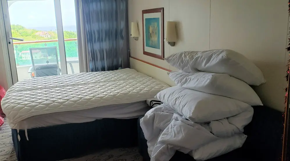 bed without sheets with pillows stacked nearby on a cruiseship in quarantine
