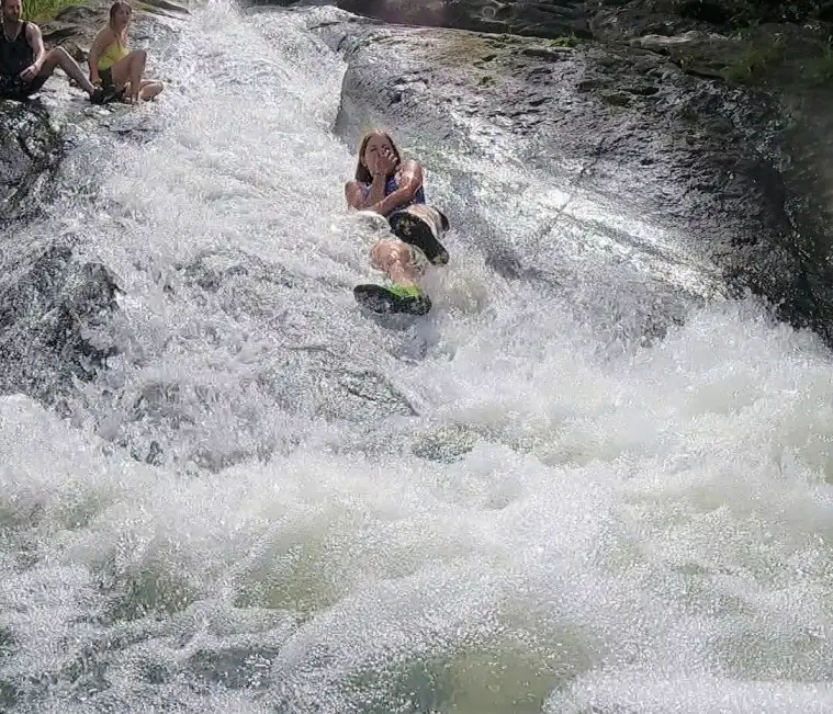 girl plugging nose as she is in the water going down a natural slide in Puerto Rico