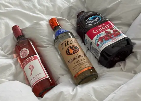 3 bottles of alcohol and juice on a bed