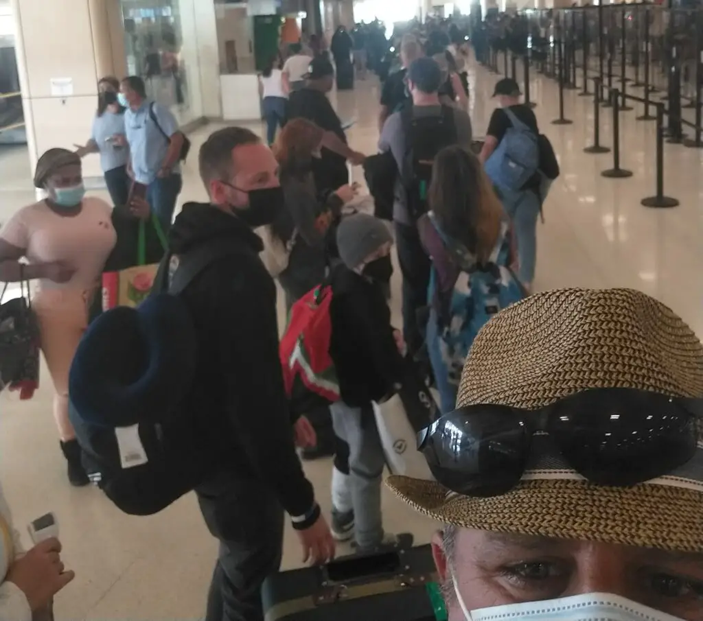 crowd of people standing in line with masks at the San Juan airport