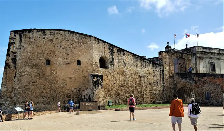 few people in the plaza in front of old stone fort Castillo de San Cristobal while touring old san juan puerto rico for one day