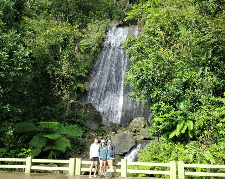 three girls standind in front of waterfall La Coca Falls - one of the first things to do in El Yunque National Forest