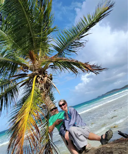 2 people sitting on a palm tree in front of the water at Zoni Beach - best beach in Culebra puerto rico