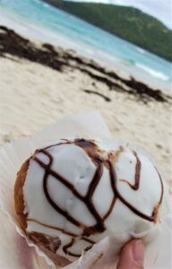 Donut from the Puertorican Bakery in front of a sandy beach and water in Puerto Rico