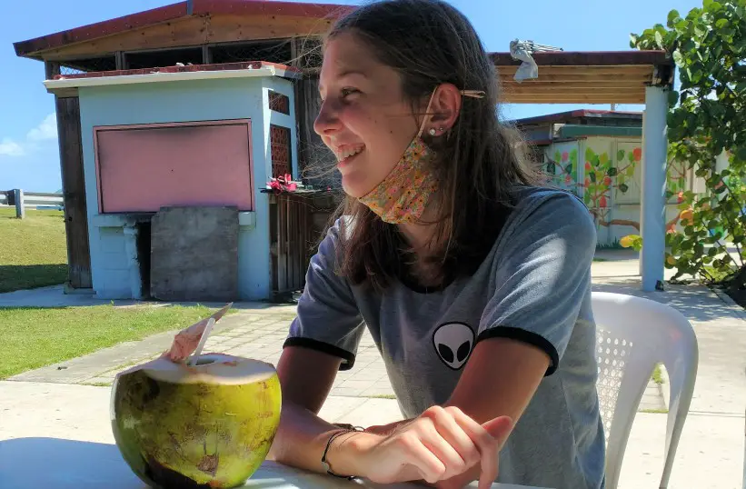 girl sitting at a table Enjoying a coconut at Pinones Beach on a Puerto Rico vacation