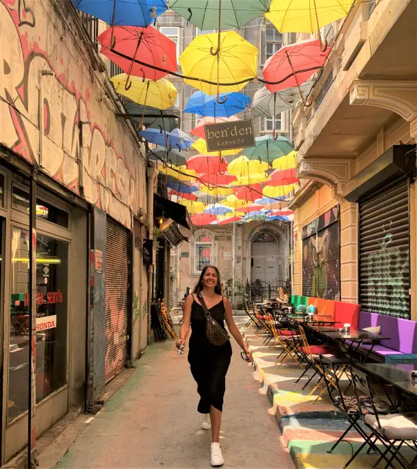 colorful umbrellas over the head of a lady posing on a street in Istanbul