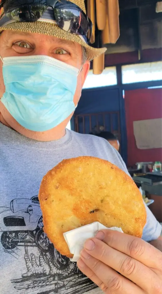 man holding a deep fried food Trying Bacalaitos at Pinones Food Kiosks in Puerto Rico