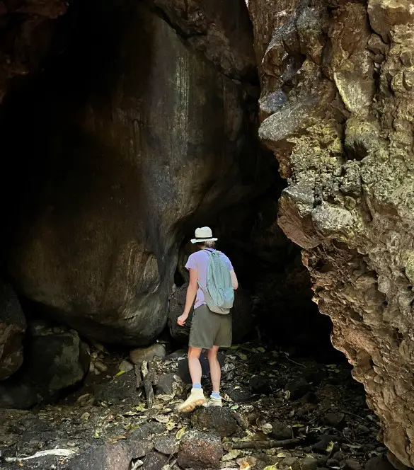 standing in front of a dark cave after hiking st kitts