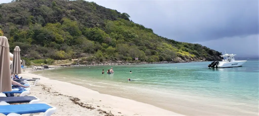 white sand and aqua caribbean water with a few people in it at Best beach in St Kitts - Reggae Beach