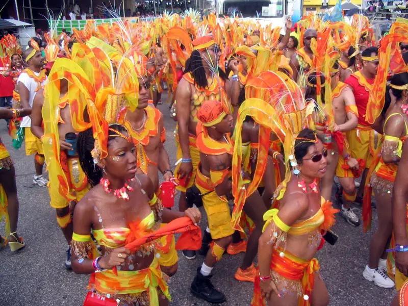 lots of people in yellow and orange dancing at carnival in trinidad
