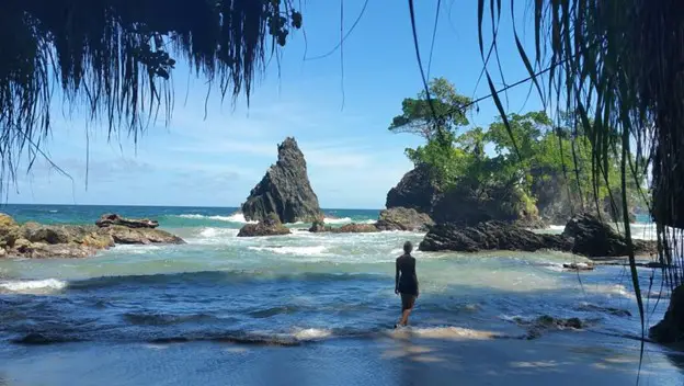 girl walking alone at the edge of the water on a beach for things to do in trinidad