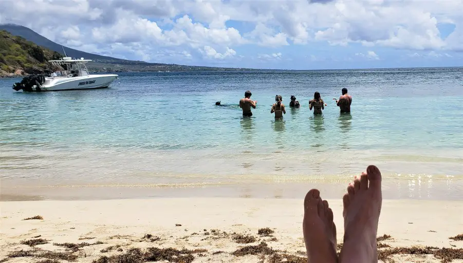 several people in the blue water putting on snorkel gear to get ready for Snorkeling in St Kitts at Reggae Beach