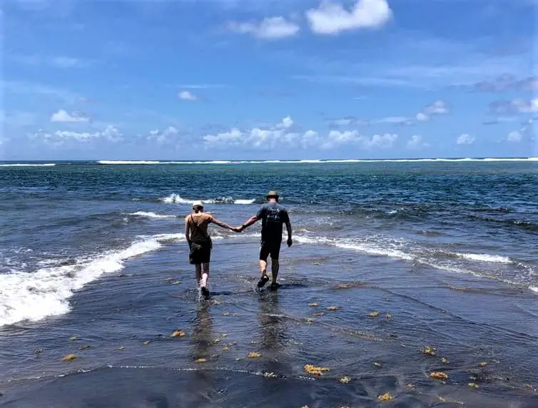 two people holding hands and Walking between the ocean and the sea on Dieppe Bay in St Kitts in the Caribbean