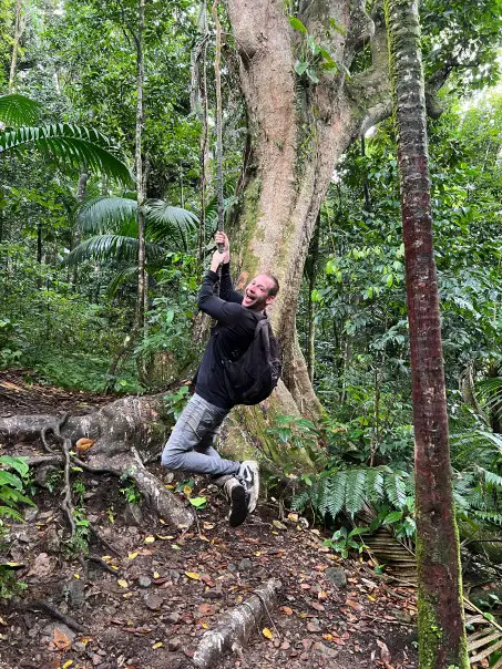 man with happy expression hanging on vine on Mt Liamuiga in the rainforest