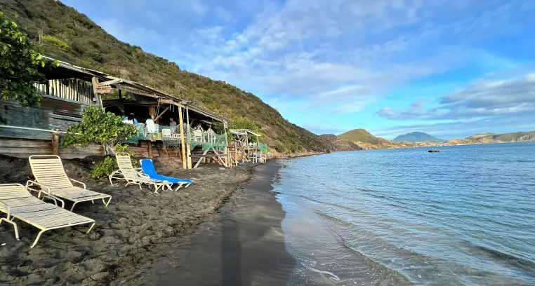 sandy beach, lounge chairs and a bar in the background at shipwreck beach in St Kitts and Nevis